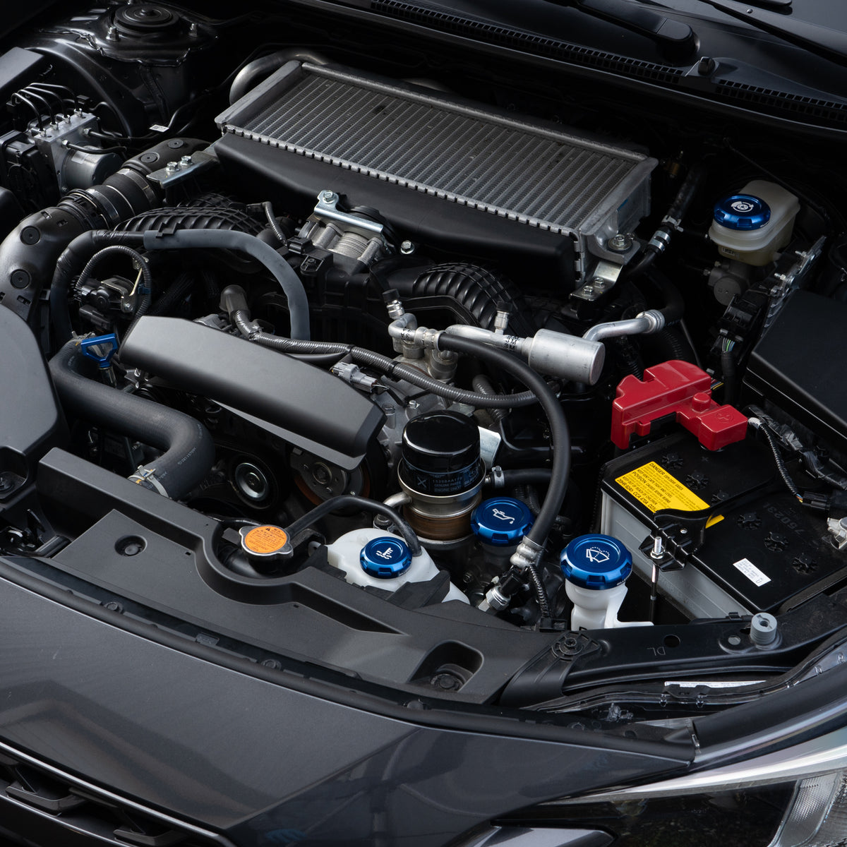 Blue Billetworkz engine bay caps installed in a Subaru engine bay