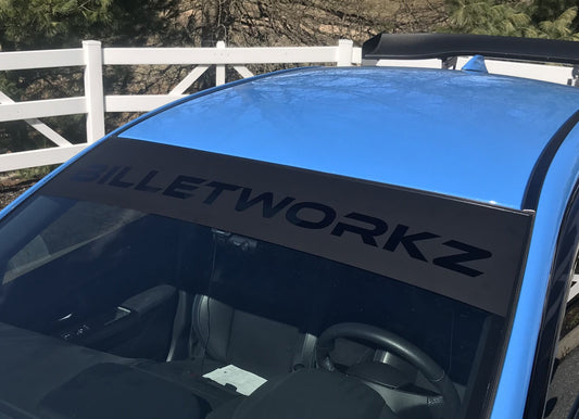 A black rectangular reverse windshield banner with the 'Billetworkz' logo displayed on a blue vehicle.