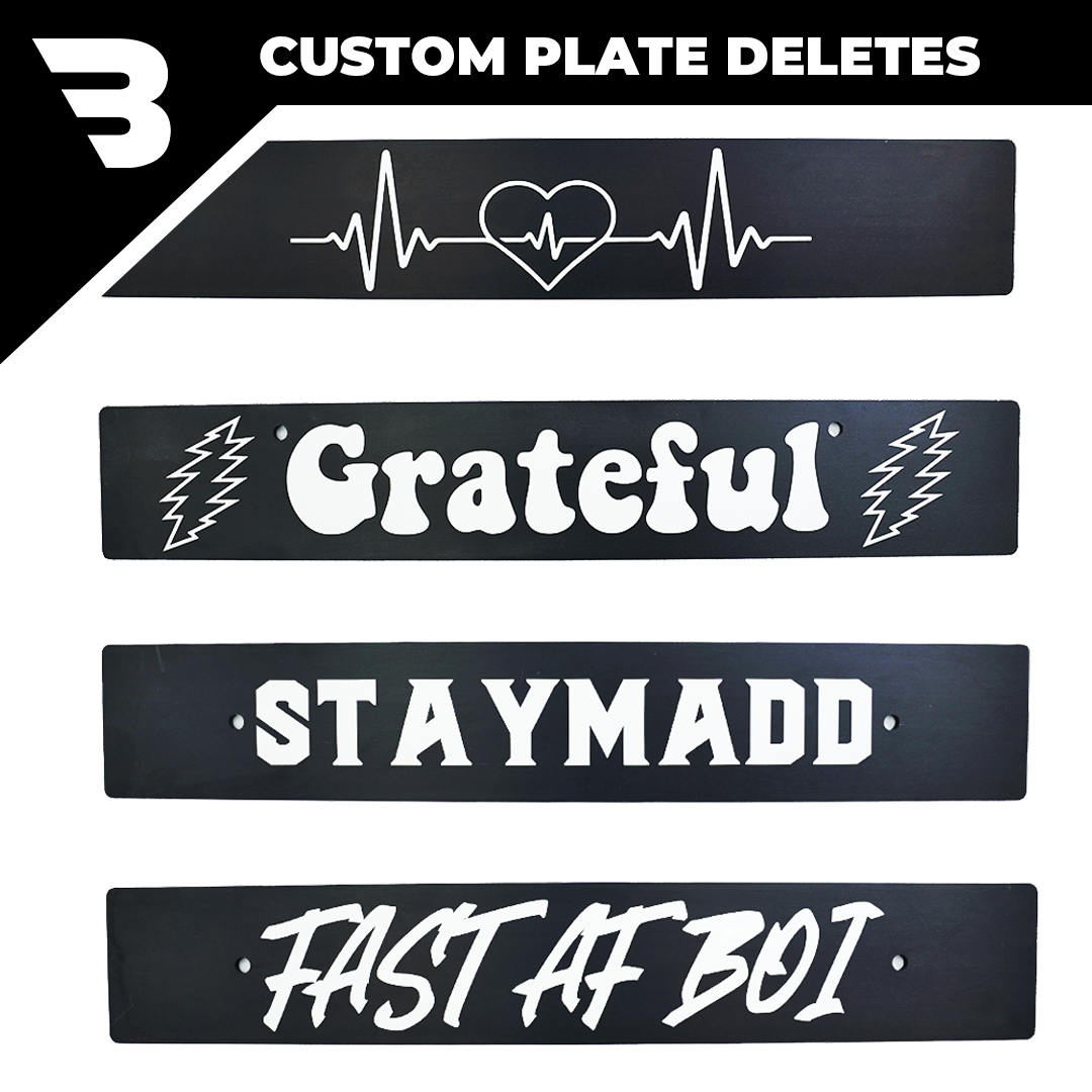 A collection of custom engraved license plate deletes with various engravings and text, mounted on a white background.