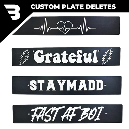 A collection of custom engraved license plate deletes with various engravings and text, mounted on a white background.