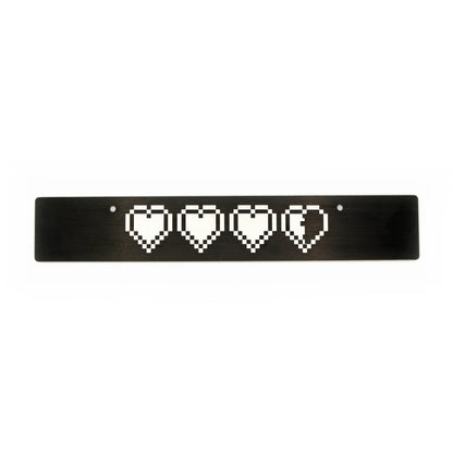 A black anodized aluminum front license plate delete with a pattern of white hearts in a row centered on the plate.
