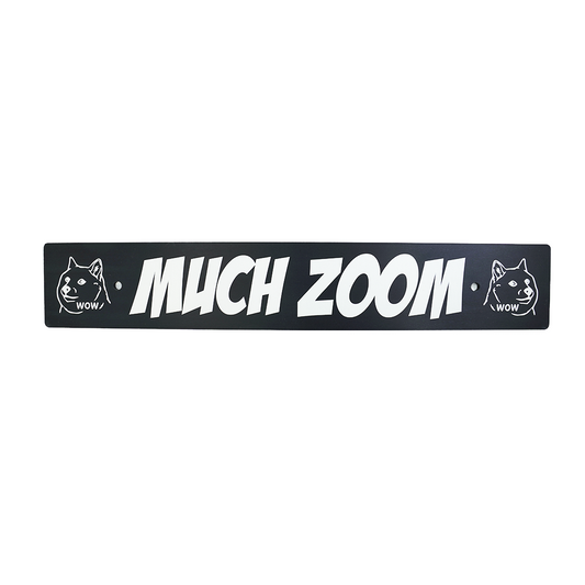 A black anodized aluminum license plate delete with the text 'MUCH ZOOM' in white, along with two cartoon images of Doge on the ends.