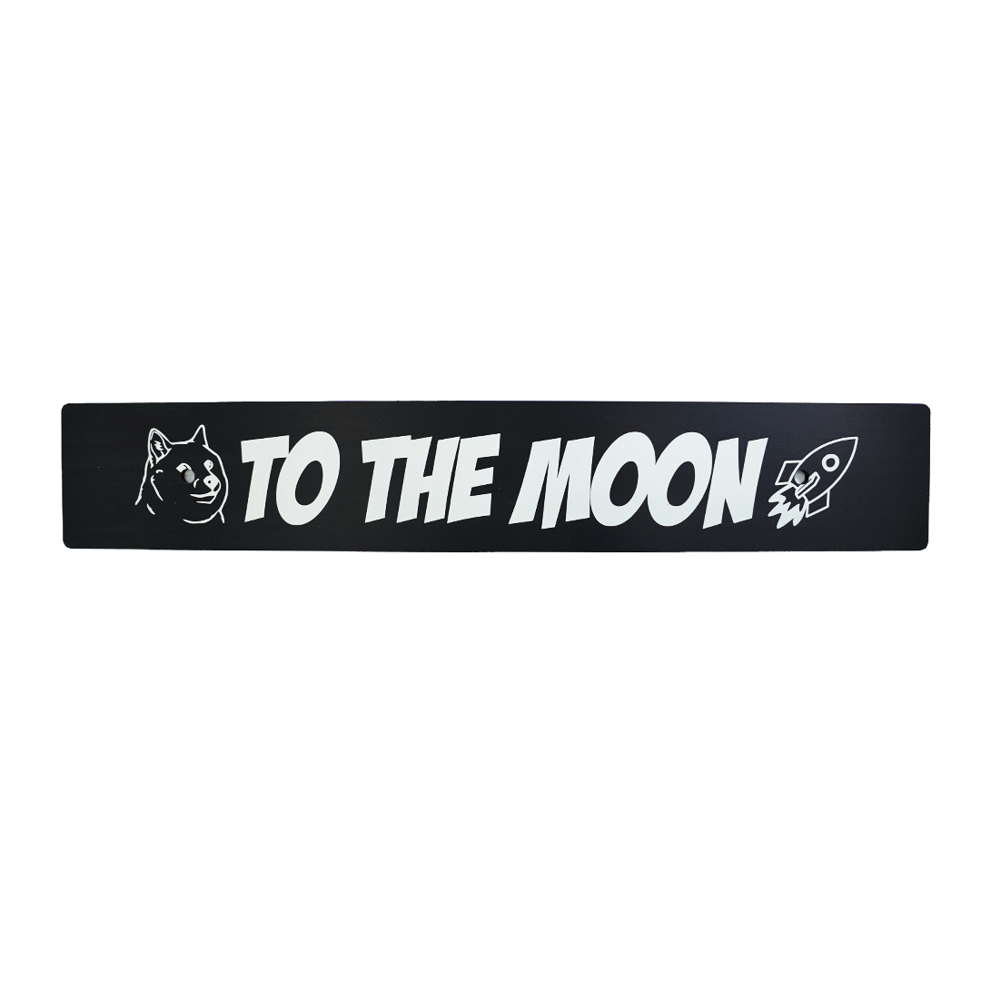 A black anodized aluminum front license plate delete with 'TO THE MOON' text and a rocket illustration in white.