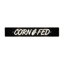 A black anodized aluminum license plate delete with the text 'CORN FED' cut out in the center.