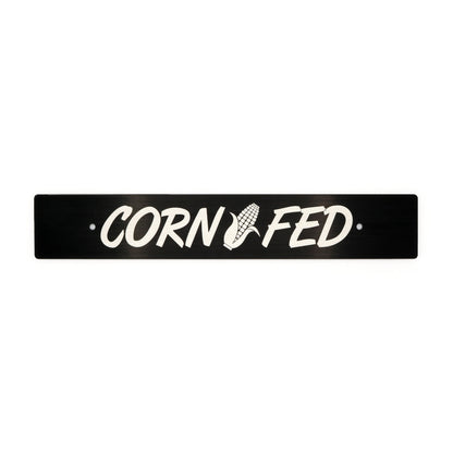 A black anodized aluminum license plate delete with the text 'CORN FED' cut out in the center.